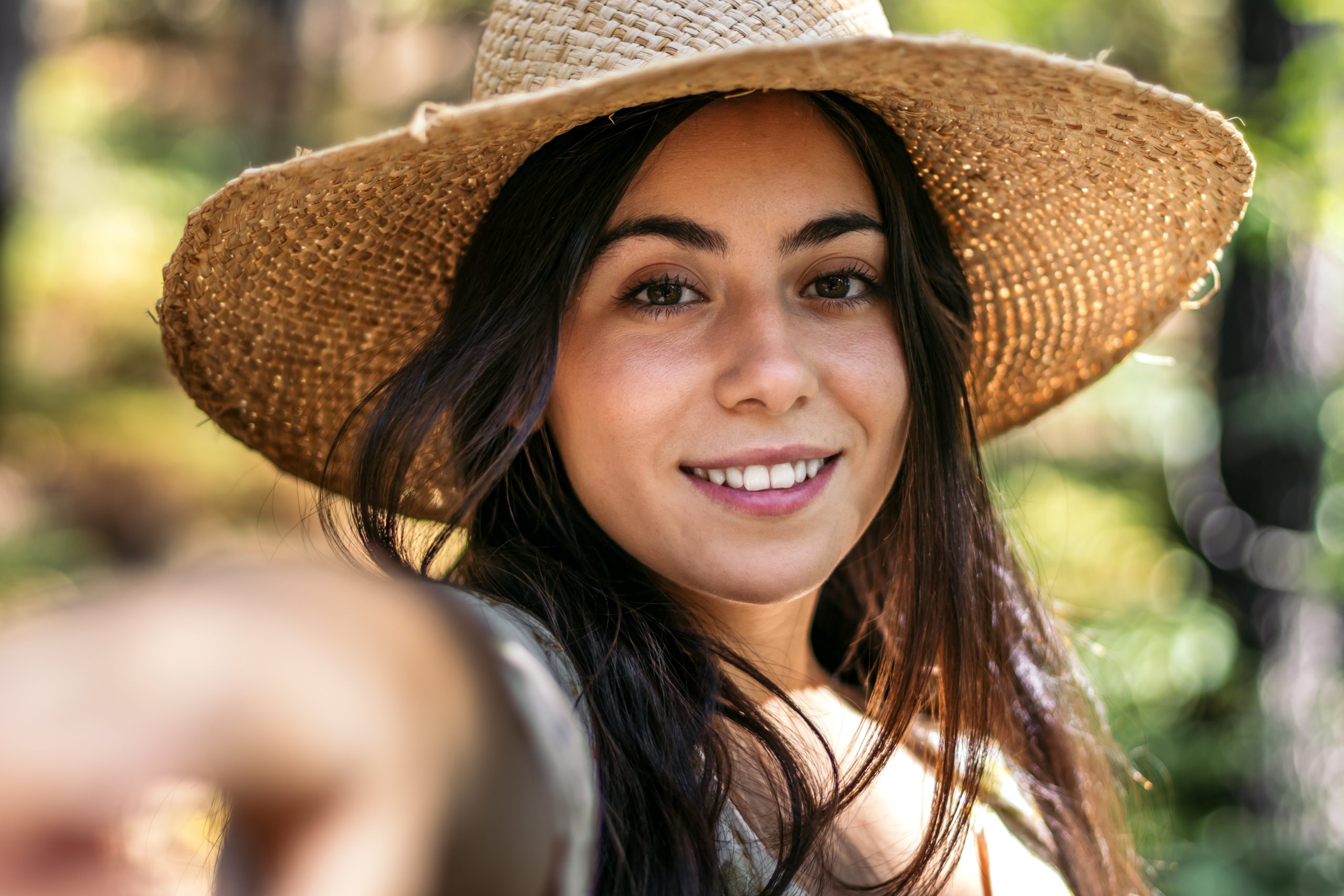 Portrait of a young beautiful woman with a straw hat enjoying a day in nature in the forest
